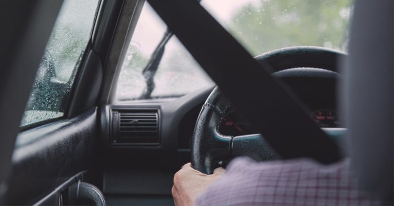 Hands on steering wheel of car