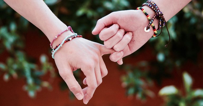 Two hands with friendship bracelets on