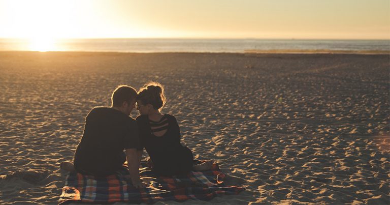 Couple sitting on beach and sunset