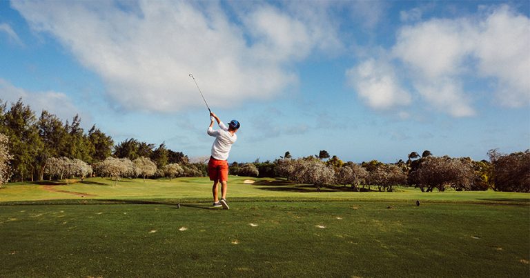 Young man swinging golf club