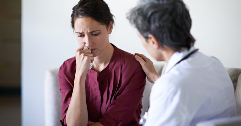 Woman looking upset with doctor comforting her