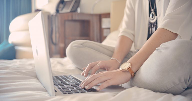 Woman sitting on bed with laptop