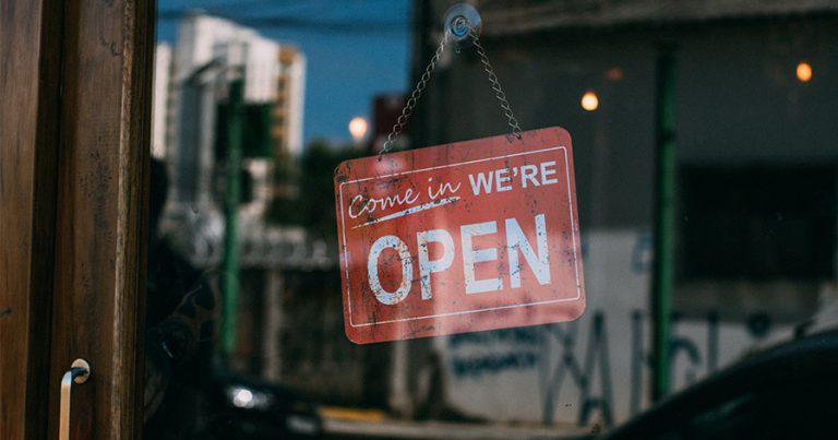 "Come in we're open" sign on glass door