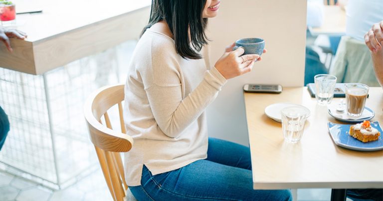 Woman sitting in cafe with phone