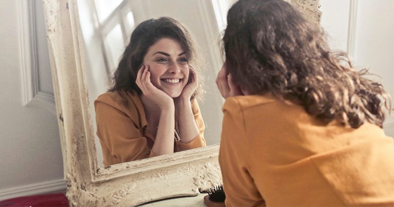 Woman staring in mirror and smiling