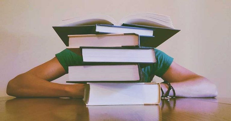 A student studying behind a pile of books