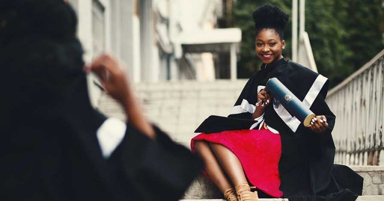 A woman poses with her PhD at a graduation ceremony