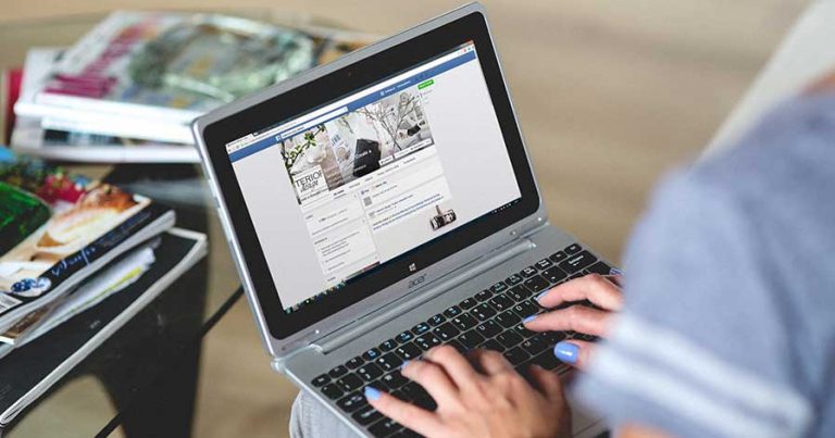 A woman working on her computer, setting up a Facebook business page