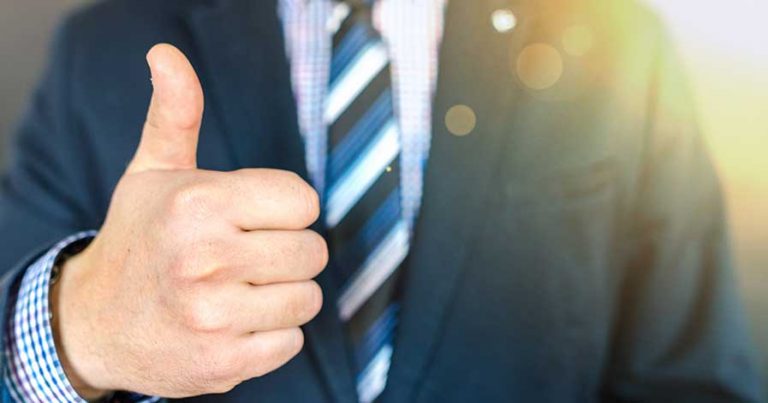 A man in a suit giving thumbs up