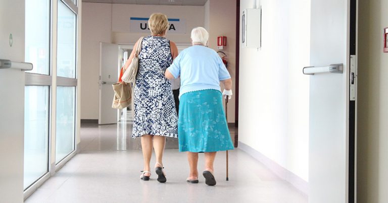 Woman and older woman walking down hall at hospital