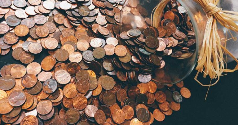 A jar of pennies being dumped out on a table