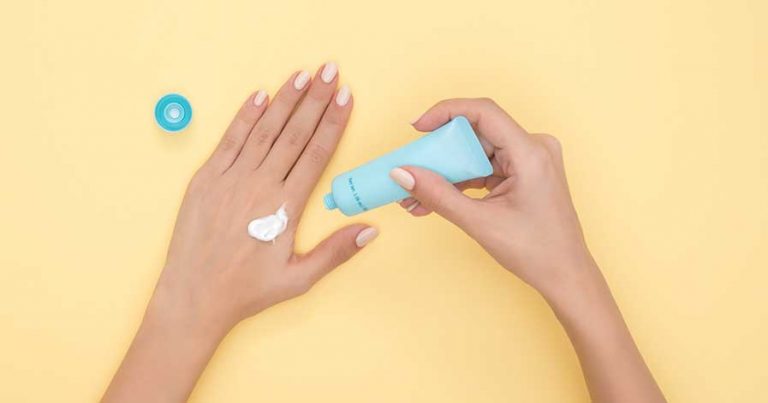A woman putting moisturizer on her hands