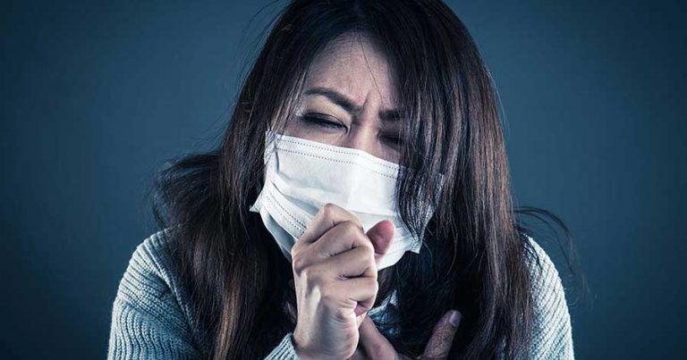 A woman sneezing into a face mask