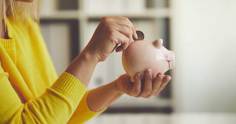 A woman putting money in a piggy bank