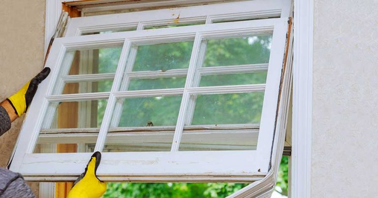 A man replacing a window in his house