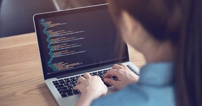 A woman writing lines of code on a laptop