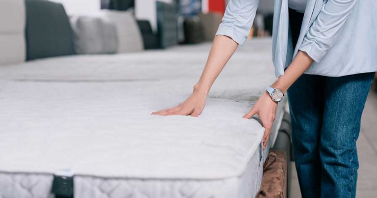 A woman feeling a mattress in a mattress store