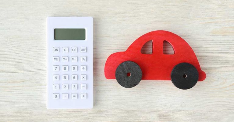 A red toy car beside a calculator