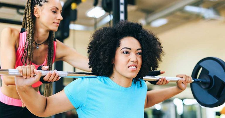 A personal trainer helping a client with weight lifting