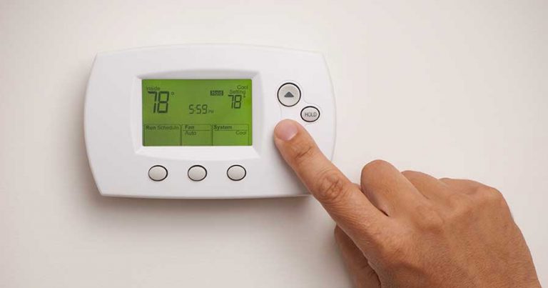 A hand adjusting the temperature on a thermostat