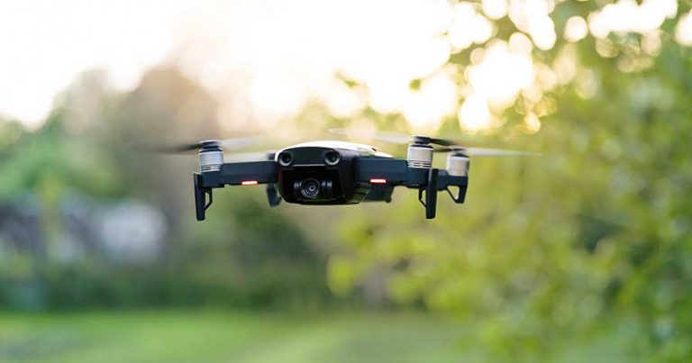 A drone flying in front of some trees