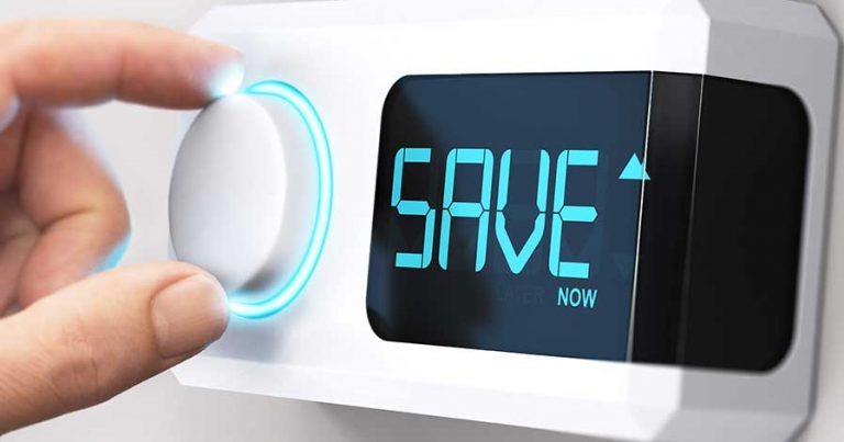 Someone adjusting a smart thermostat that says "save now"