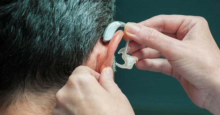 A man putting a hearing aid into his ear