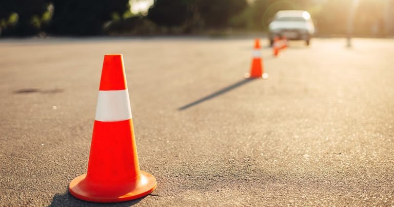 Pilons set out on pavement with car driving toward it