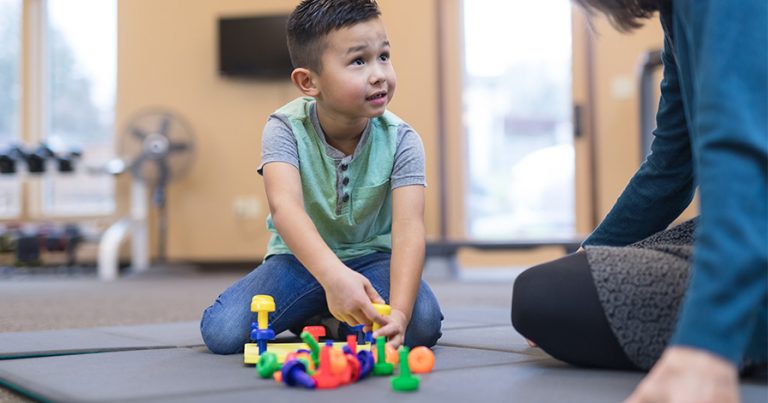Woman playing on the floor with young boy