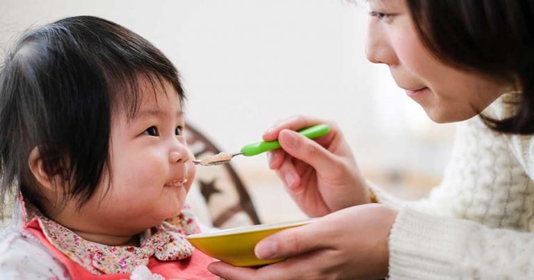 A woman feeding a baby