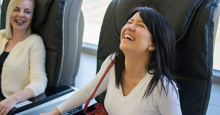 Two women sitting in massage chairs