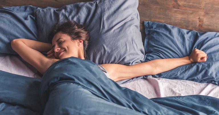 A woman laying in bed under a weighted blanket