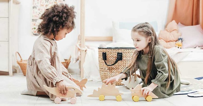 Two young girls playing with dinosaur toys