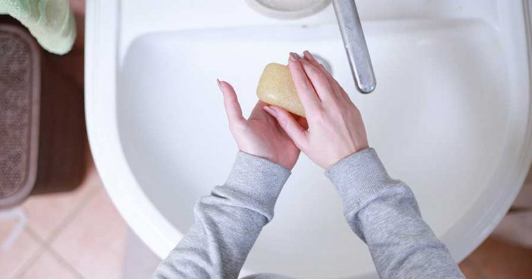 A woman washing her hands with a bar of soap.
