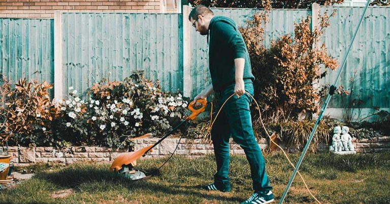A man using a lawn mower in his backyard