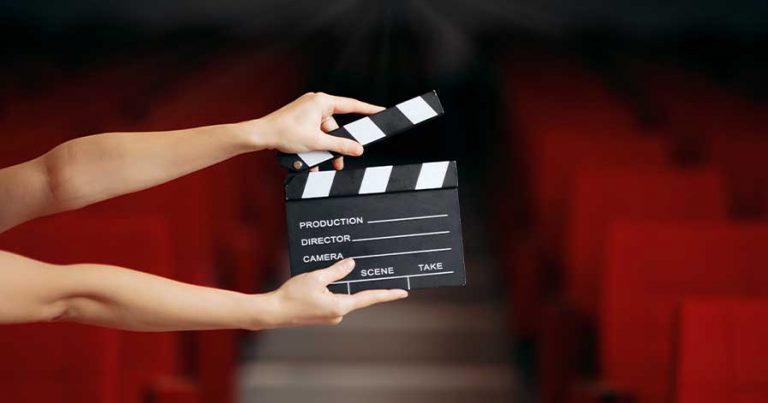 Someone holding a movie clapper in a theatre.