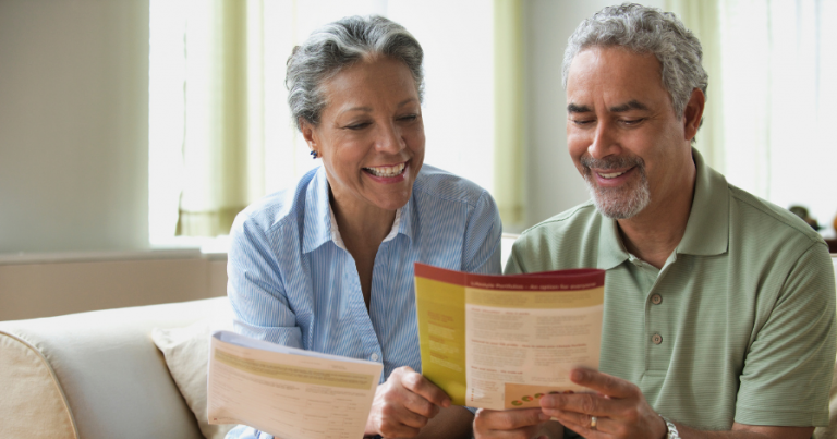 Two older adults sitting side by side, looking at paper work.