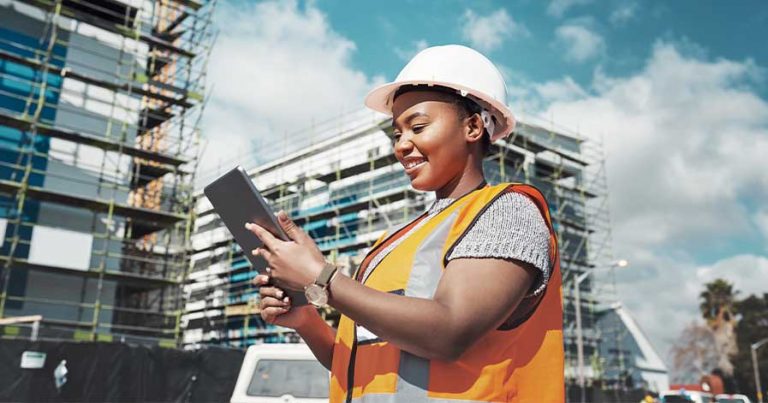 A structural engineer looking at an iPad on a construction site.