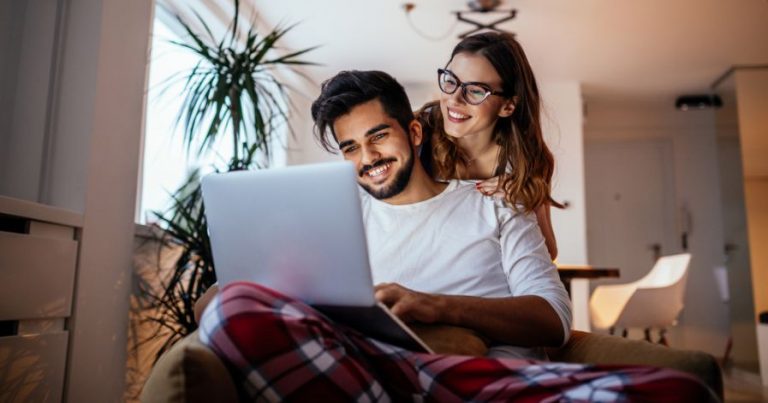 Two people sitting together, looking at a laptop