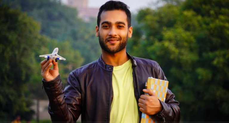 An international student from India holding a notebook and a toy plane.